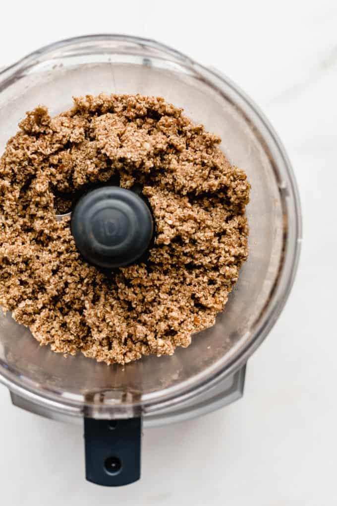 a food processor with blended pecan pie crust in it