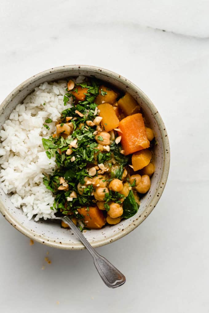 A bowl of pumpkin chickpea curry and rice with a spoon in it