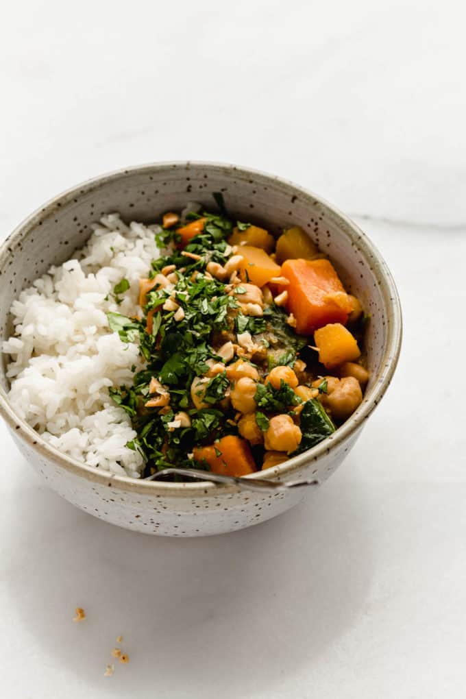 A speckled light blue bowl with rice, chickpeas and pumpkin curry in it
