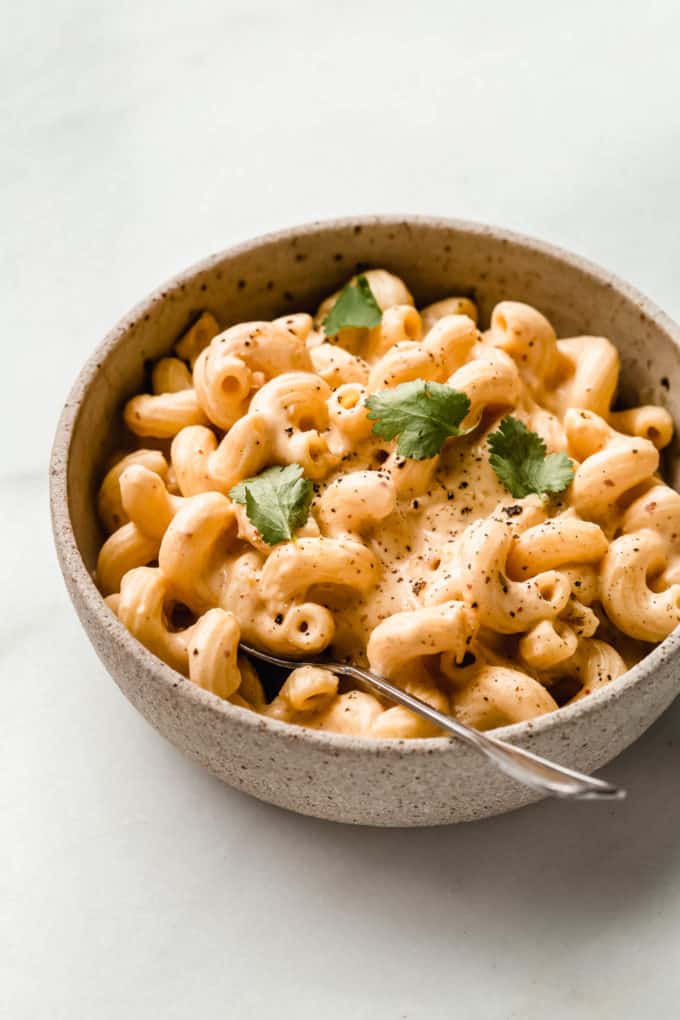 A bowl of vegan kimchi mac and cheese with a spoon in it