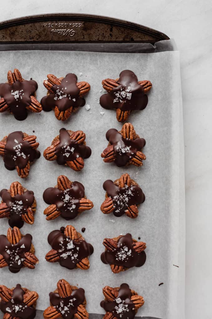 A baking sheet with parchment paper and healthy chocolate turtles on it