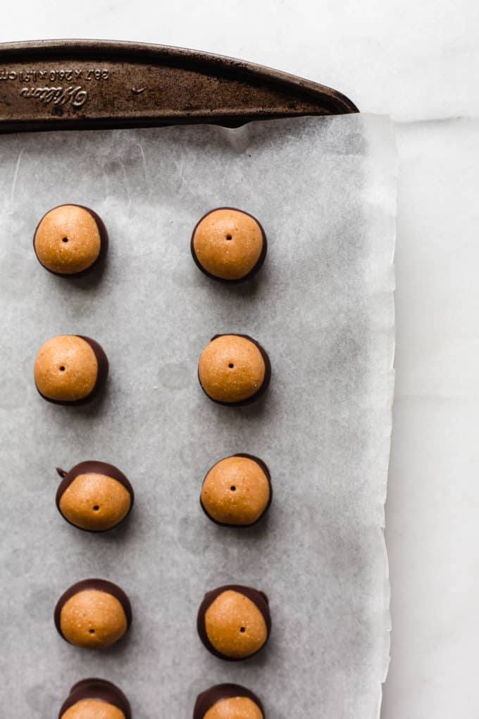 peanut butter bals dipped in chocolate on a baking sheet