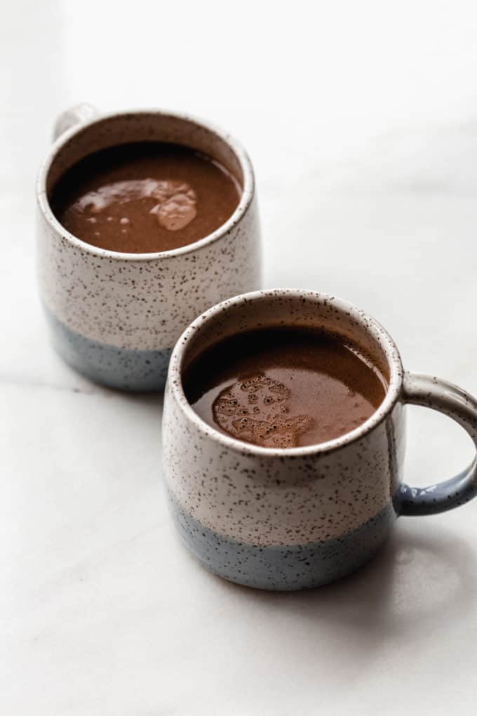 2 white and blue cups with vegan hot chocolate in them