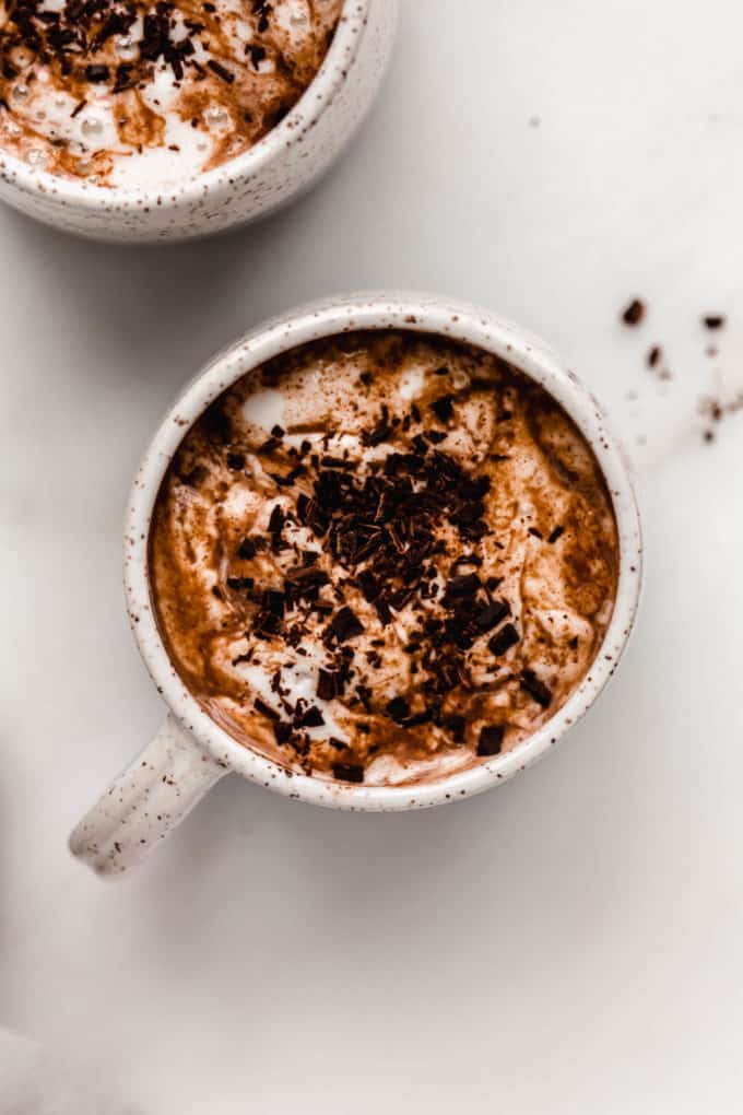 a cup filled with vegan hot chocolate topped with whipped cream and chocolate shavings