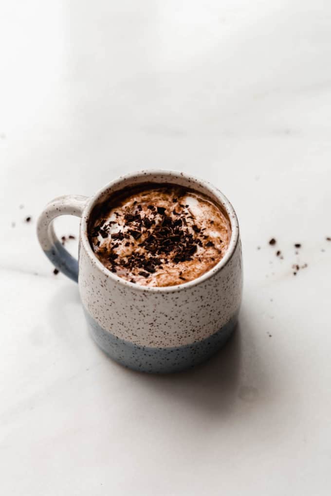 A white and light blue ceramic mug filled with hot chocolate