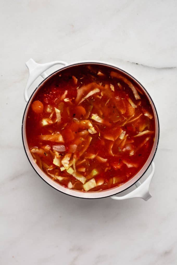 A white pot of cabbage soup on a marble board