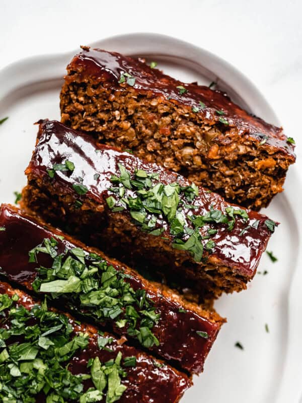 lentil loaf sliced on a white serving platter topped with chopped parsley