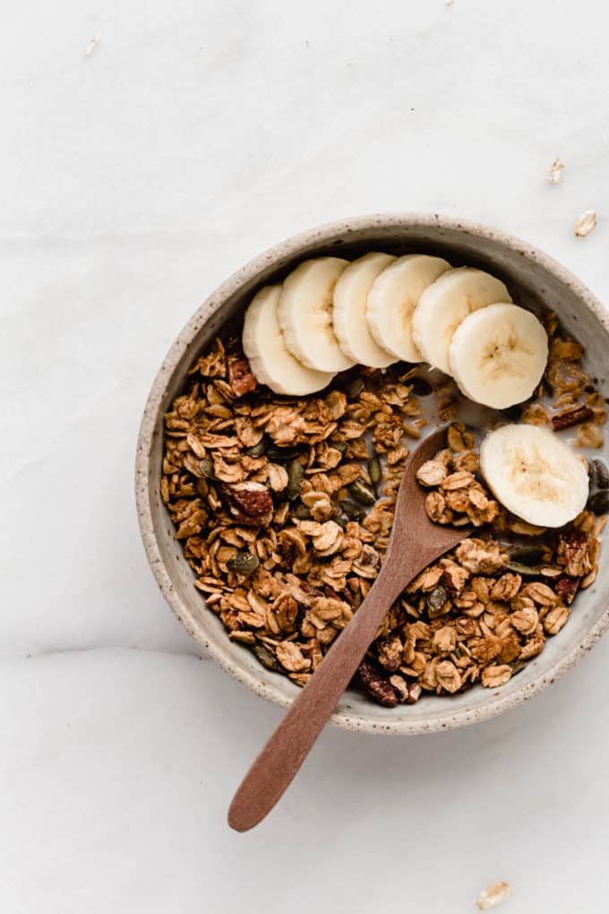 A bowl of pumpkin spice granola with sliced bananas in it