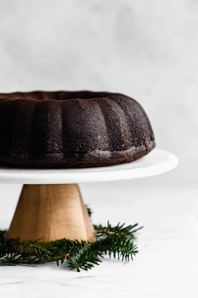 A wooden and marble cake stand with a gingerbread bundt cake on it