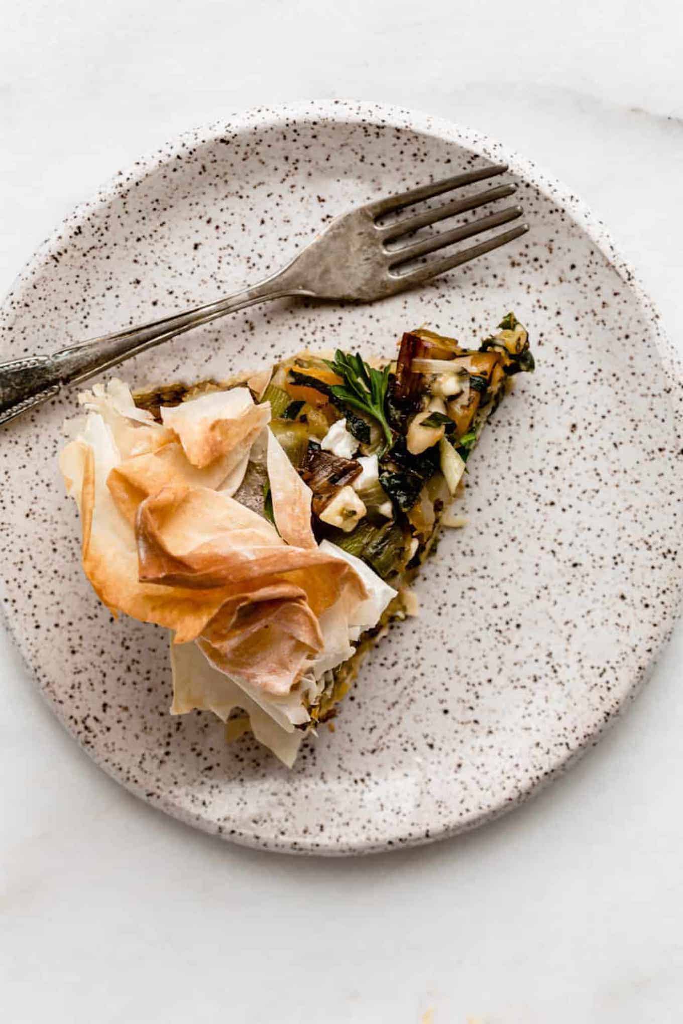 one slice of veggie skillet phyllo pie on top of a speckled plate