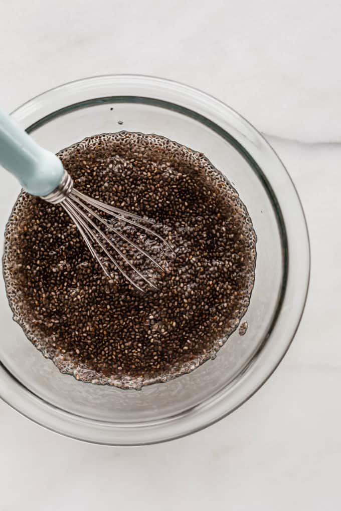 gelled chia seeds in a clear mixing bowl with a whisk