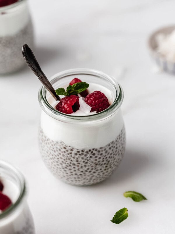 A cup of chia seed pudding topped with yogurt and raspberries