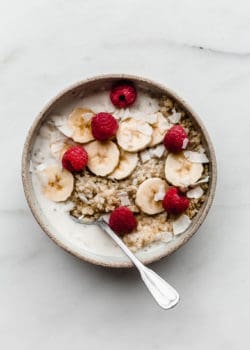 Quinoa in a ceramic bowl with coconut milk bananas and berries in it
