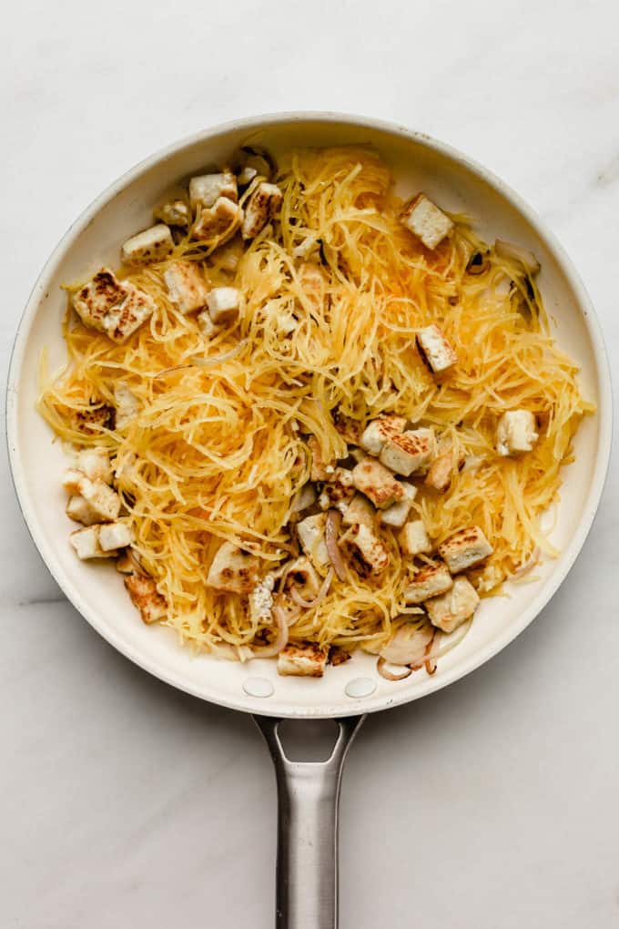 A white pan with spaghetti squash and tofu in it