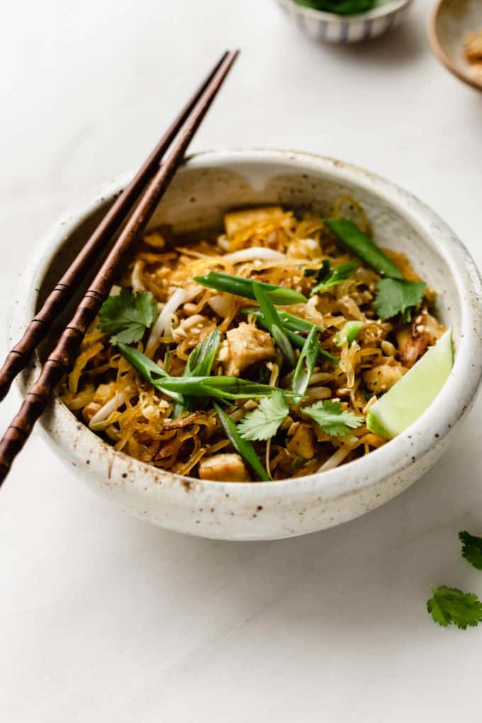 A bowl of spaghetti squash pad thai topped with sliced green onions