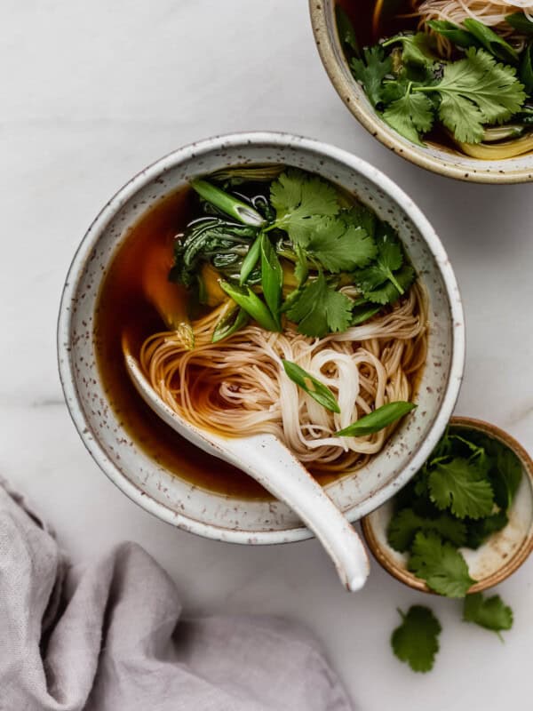 A bowl of vegan pho soup with rice noodles, cilantro and green onions