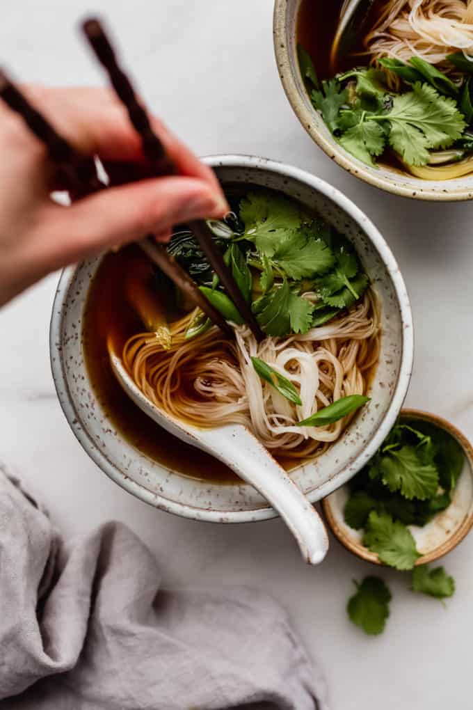 A bowl of vegan pho with chopsticks in it