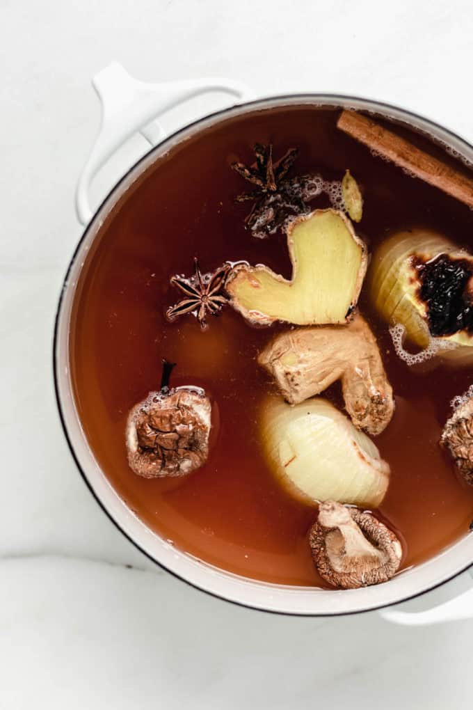 A pot of vegan pho broth with spices in it
