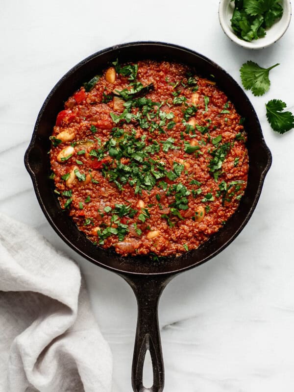 A vegan shakshuka in a cast iron skillet topped with parsly and a napkin and parsley on the side
