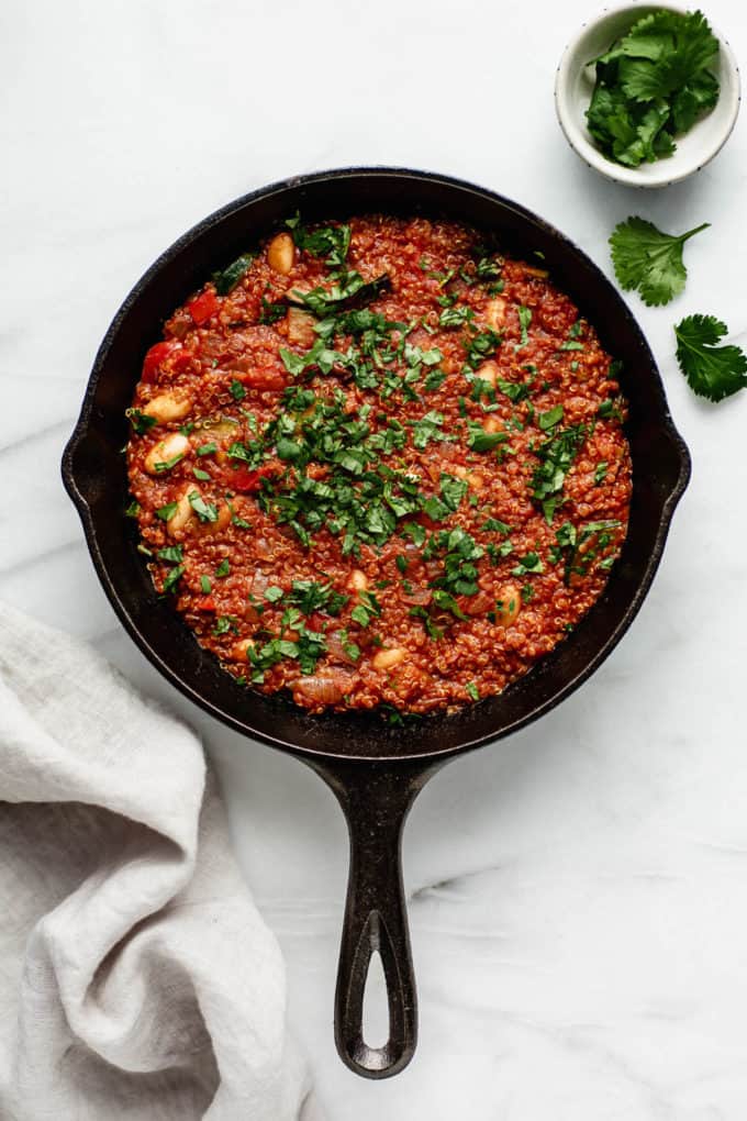 A vegan shakshuka in a cast iron skillet topped with parsly and a napkin and parsley on the side