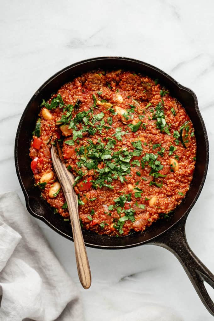 A vegan quinoa shakshuka with a wooden spoon in it
