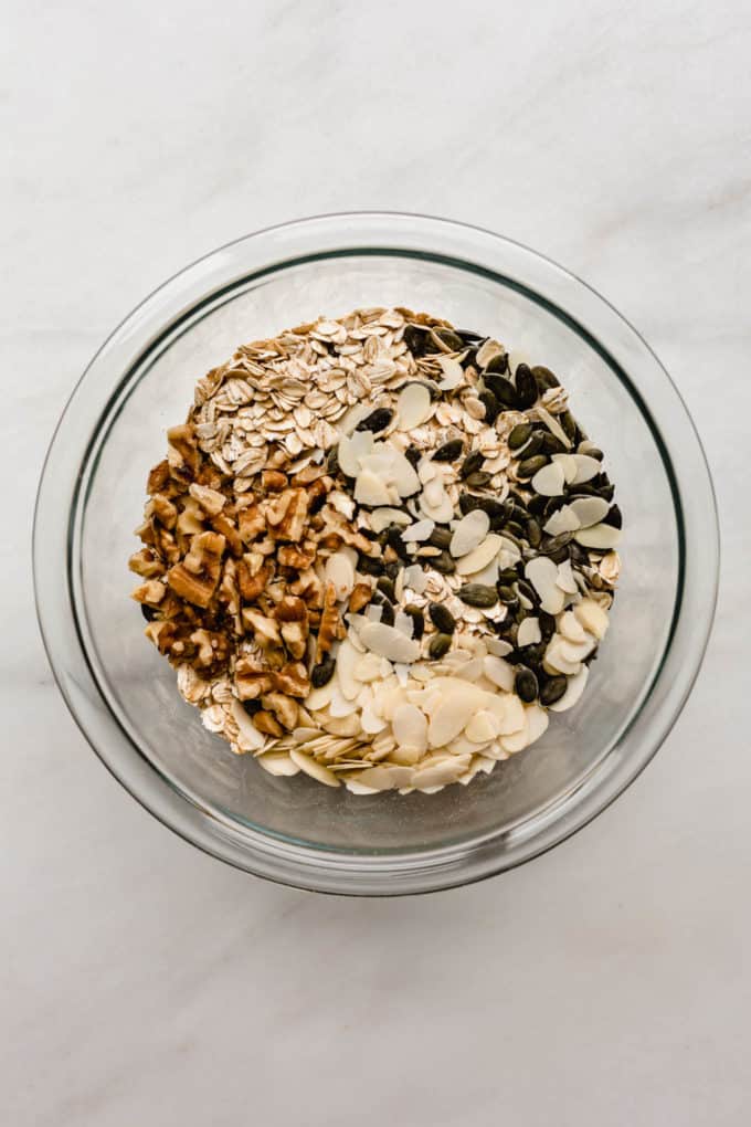 walnuts, almonds, pumpkin seeds and oats in a clear mixing bowl