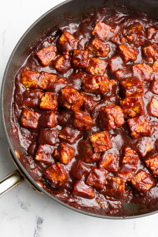 A skillet with saucey tempeh cubes in it