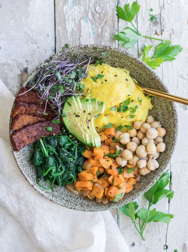 A breakfast bowl with polenta, tempeh and vegetables in it