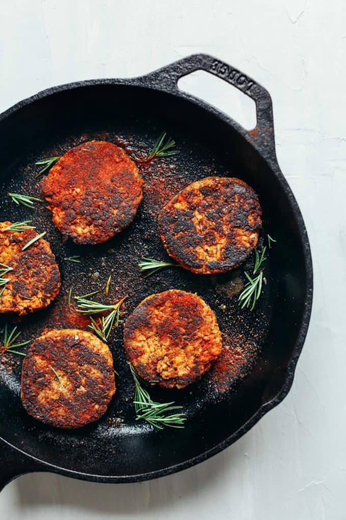 A cast iron skillet with tempeh patties in it