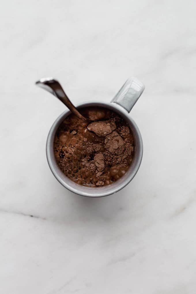 A grey mug with raw batter for a mug cake in it