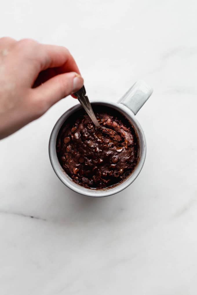 Vegan chocolate mug cake in a grey mug with a spoon in it