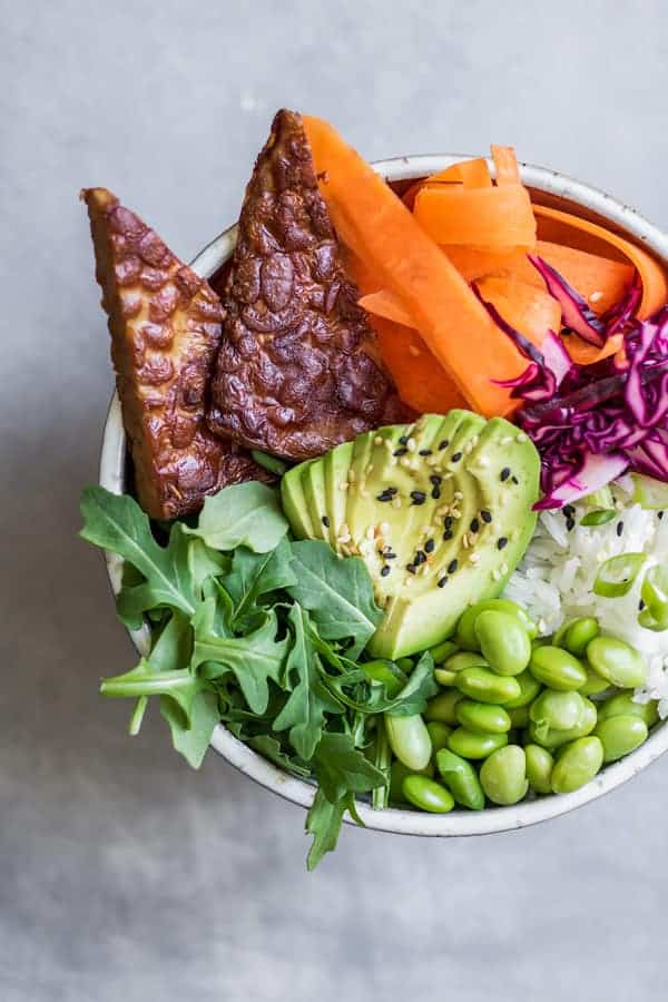 A bowl with vegetables, avocado and grilled tempeh in it
