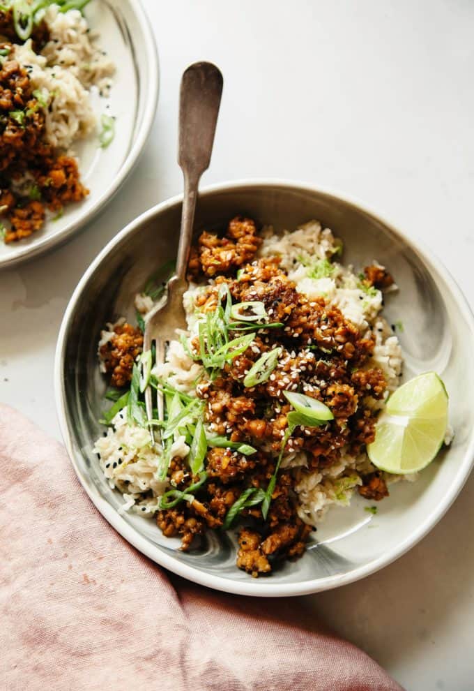 A white and grey bowl with rice and tempeh in it
