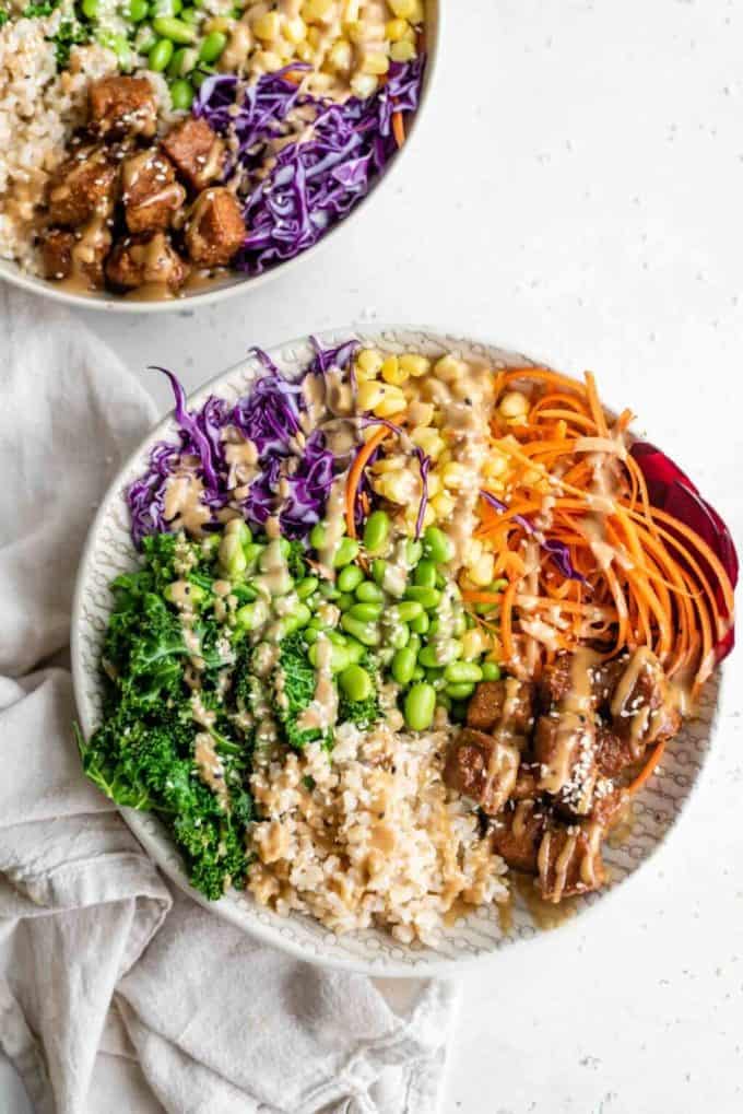 A buddha bowl with rice, vegetables and tempeh in it