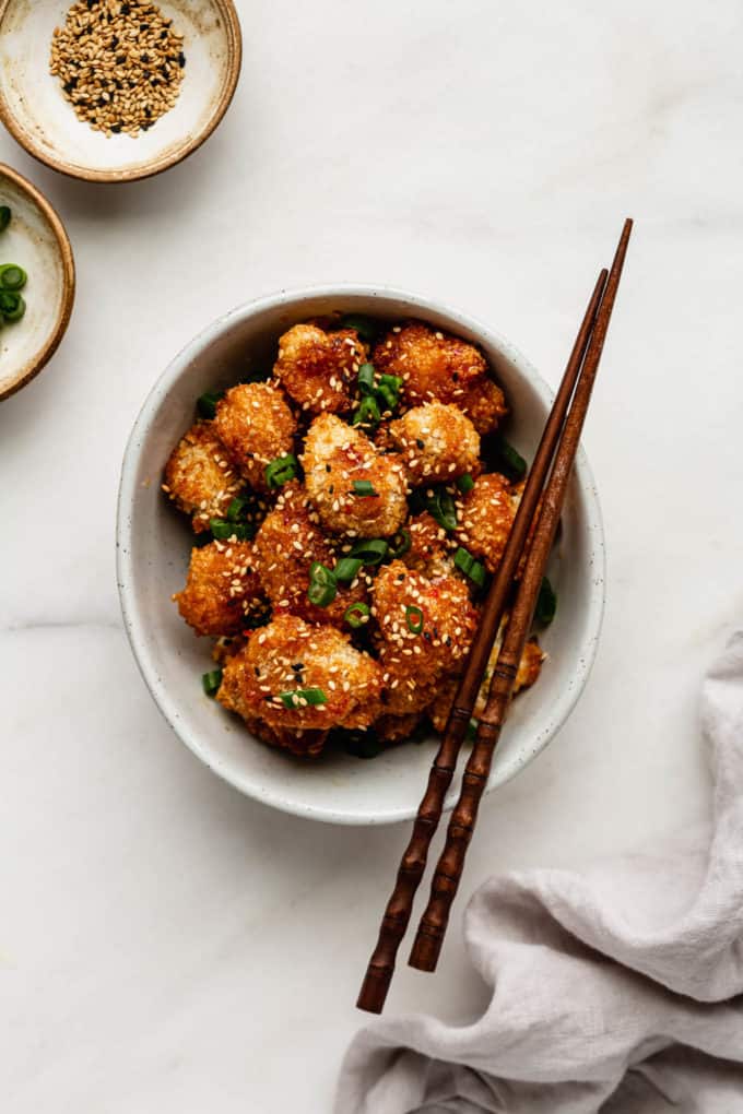 a bowl of bang bang cauliflower with chopsticks and napkin