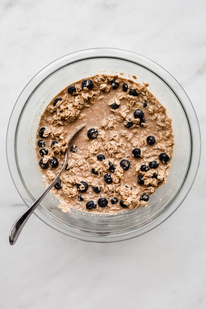 a clear mixing bowl with oats and blueberries