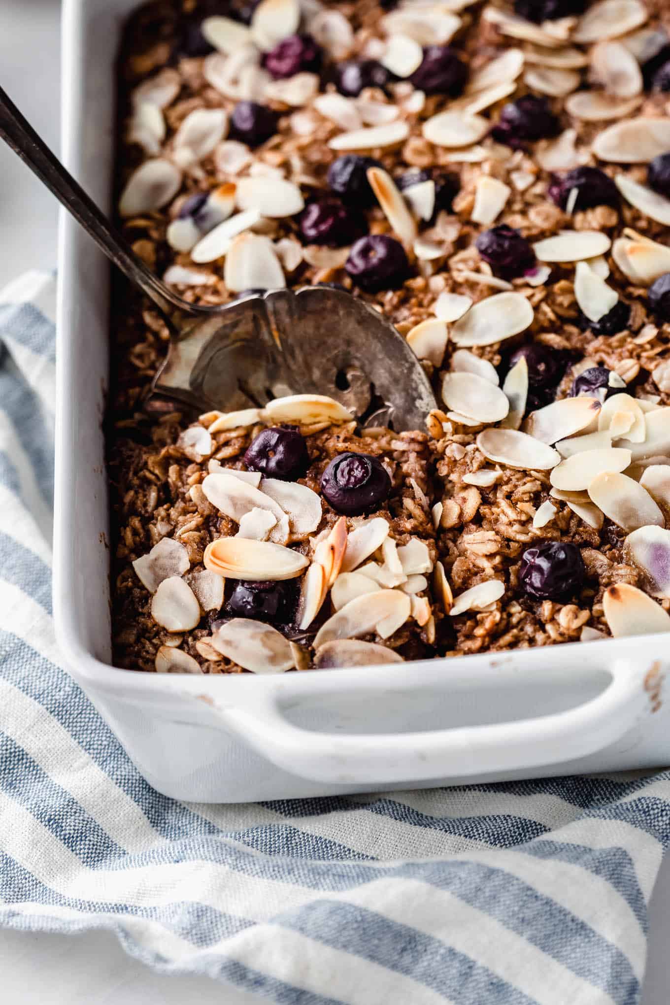 a spoon of baked oatmeal being scooped out of a baking dish
