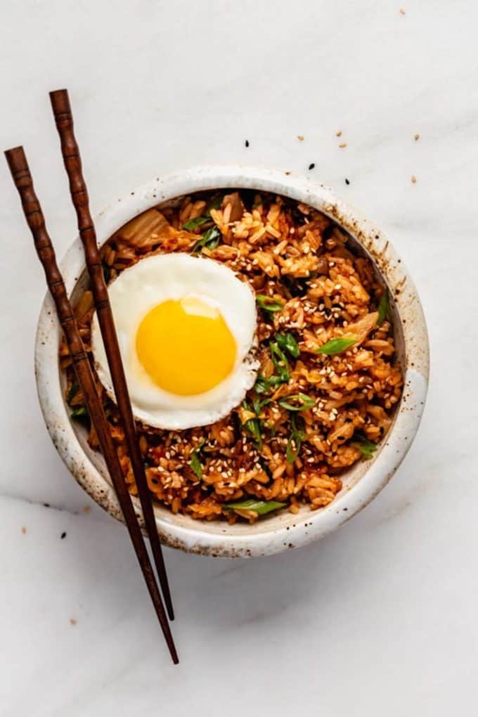kimchi fried rice with a fried egg on top in a bowl with chopsticks on the side