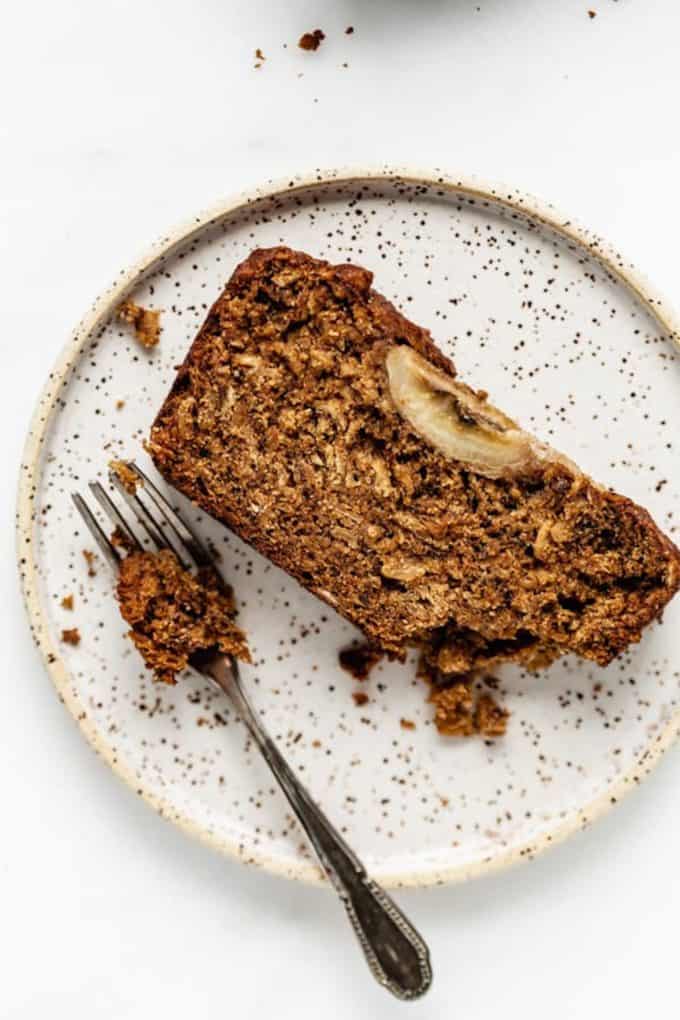 vegan banana bread on a white speckled plate with a fork