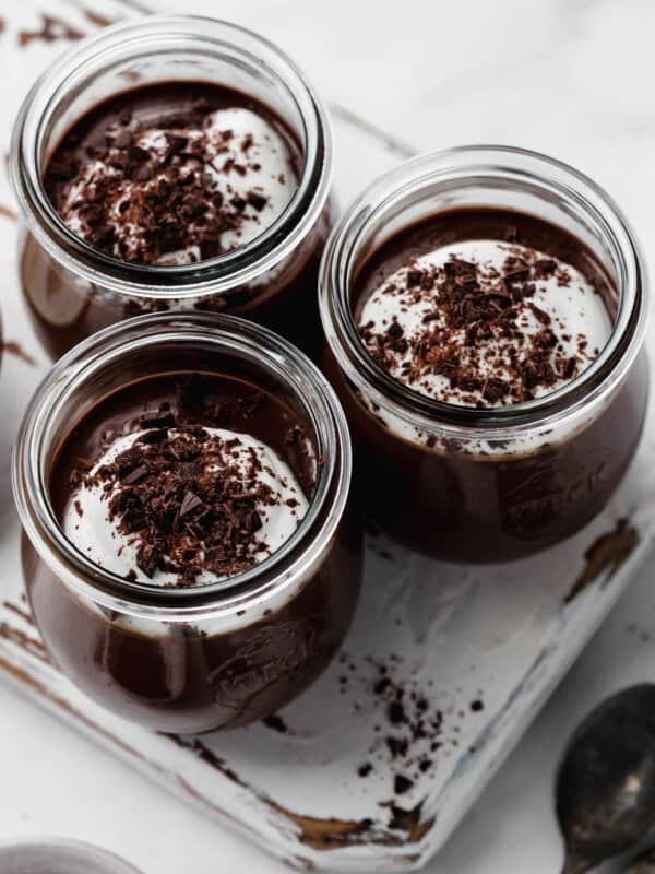 three small jars filled with chocolate topped with shredded dark chocolate