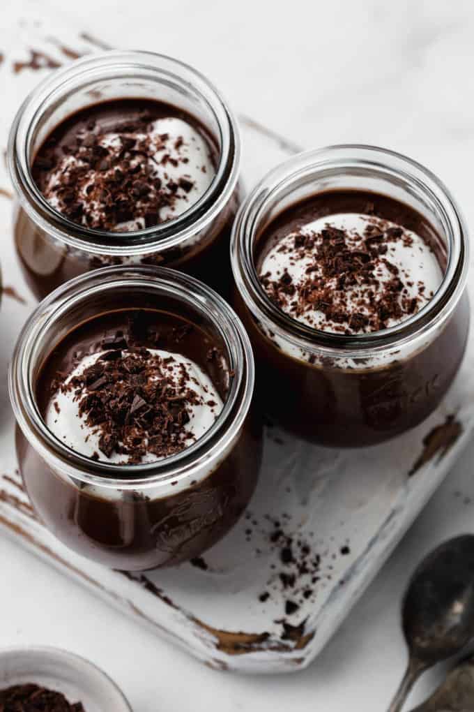three small jars filled with chocolate topped with shredded dark chocolate