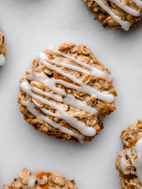 A carrot cake cookie topped with glaze on a marble board