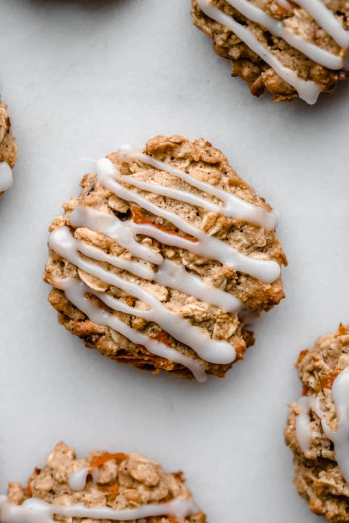 A carrot cake cookie topped with glaze on a marble board