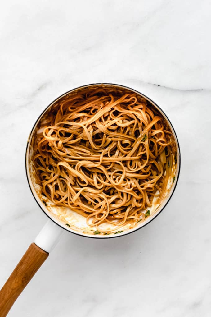 Peanut butter noodles in a white pot with a wood handle