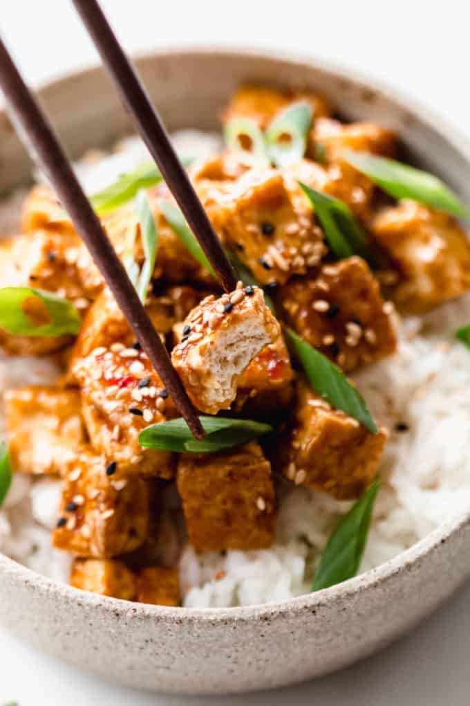 chopsticks picking up a cube of teriyaki tofu