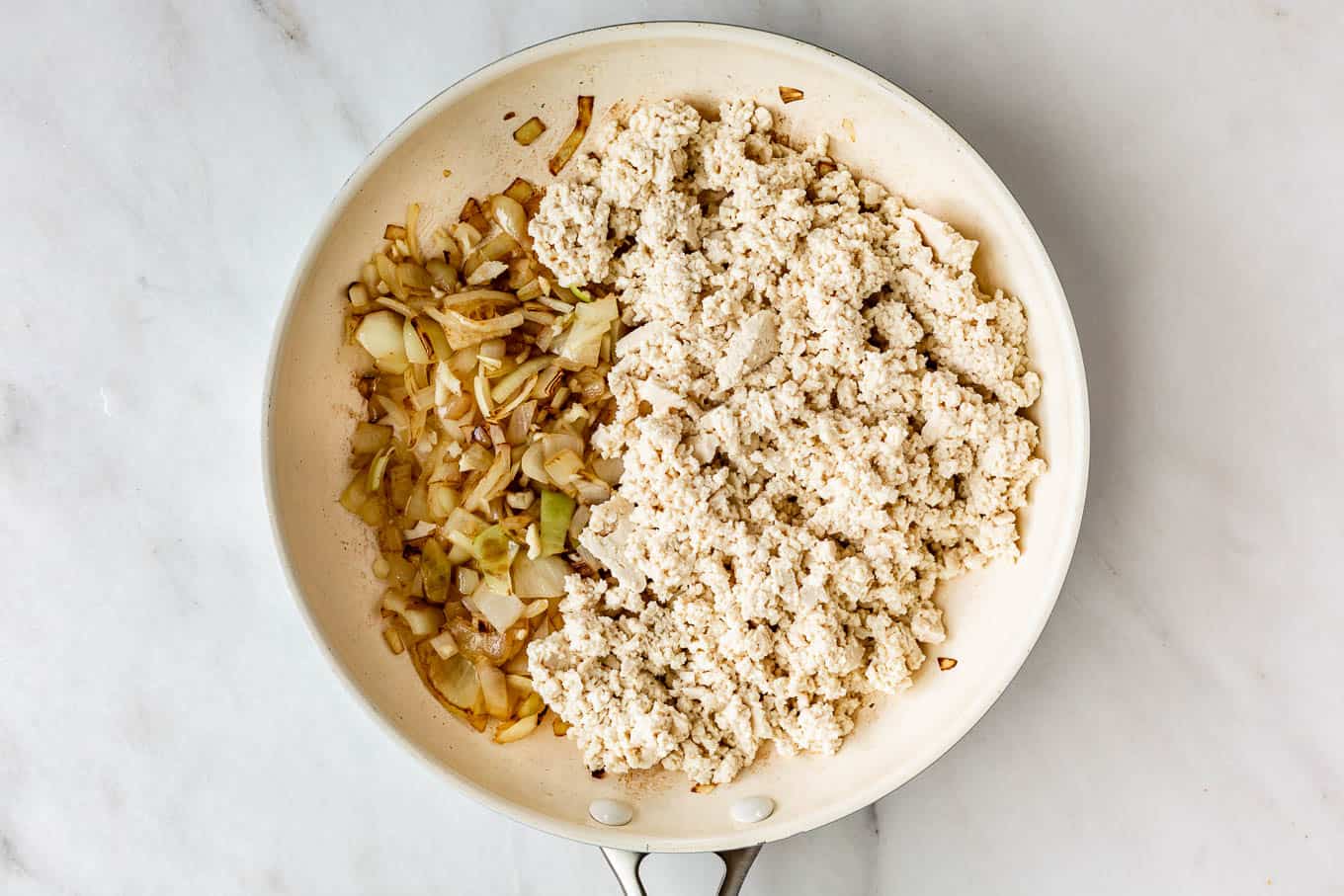 crumbled tofu, onions and garlic in a white pan