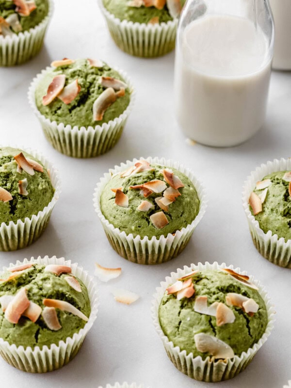 matcha coconut muffins on a marble counter with a jar of milk