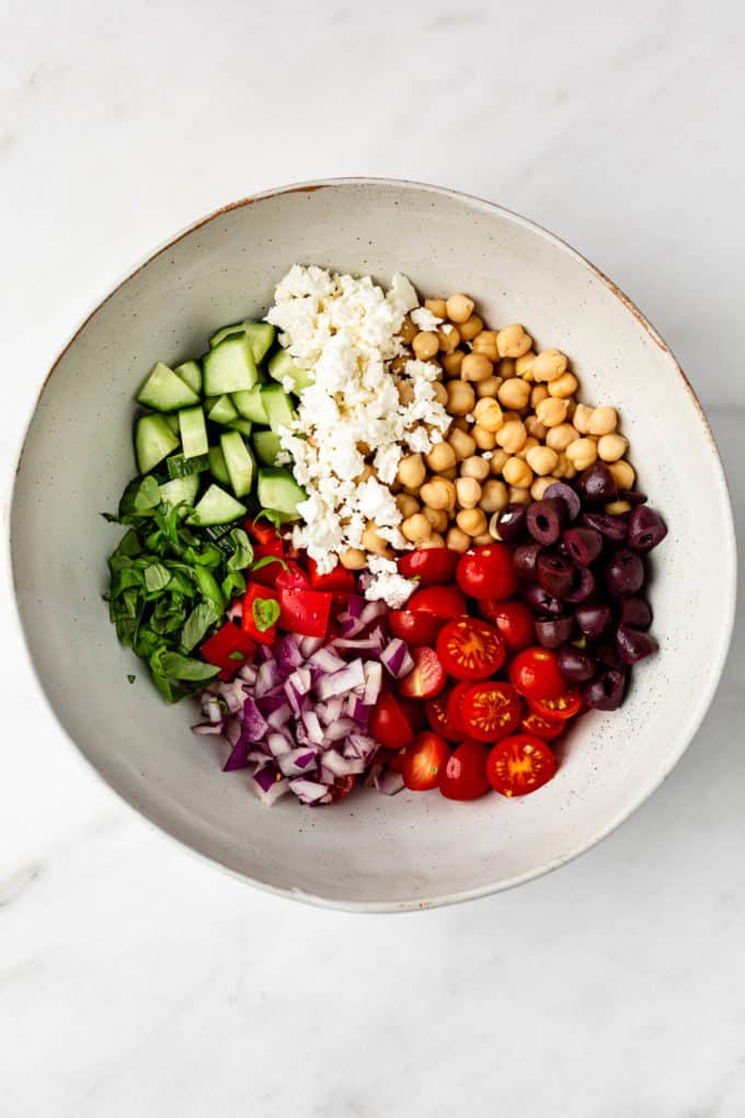 Chickpeas, feta, olives, tomatoes, cucumbers and red peppers in a bowl