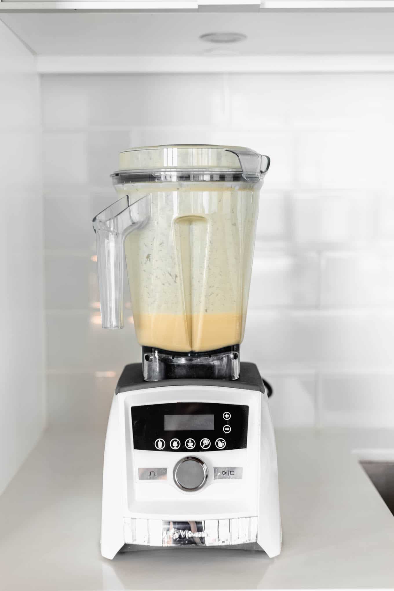 A white blender with orange smoothie in it