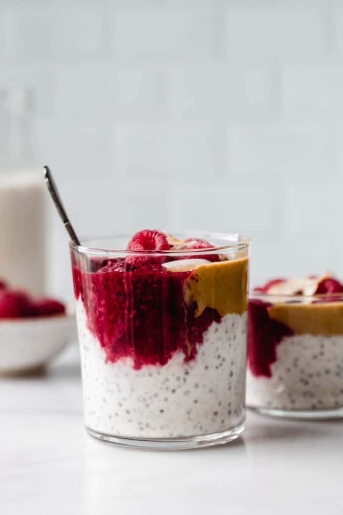 a cup filled with overnight oats, peanut butter and raspberry jam